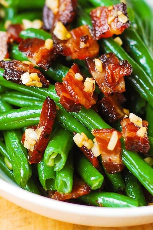 Sautéed green beans with crispy bacon bits and garlic in a skillet